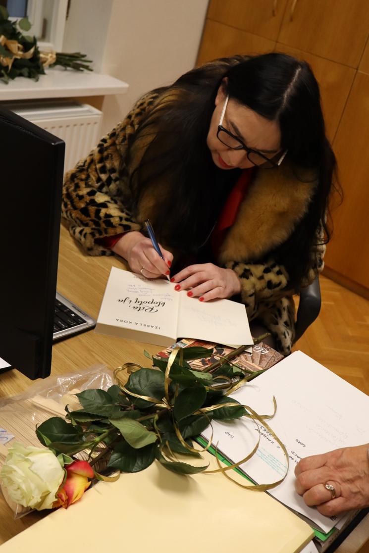 kolorowe zdjęcie, grupa ludzi siedzi na krzesłach, zdjęcie na tle książek