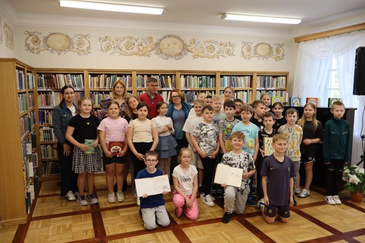 kolorowe zdjęcie, 3 osoby, 2 kobiety i 1 mężczyzna, pozują do zdjęcia na tle książek 
