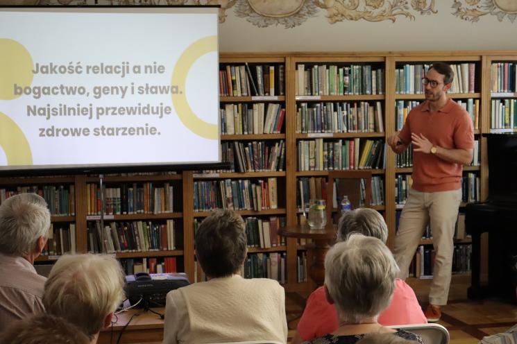 kolorowe zdjęcie, 6 osób, 5 siedzi, 1 stoi i przeprowadza prezentację