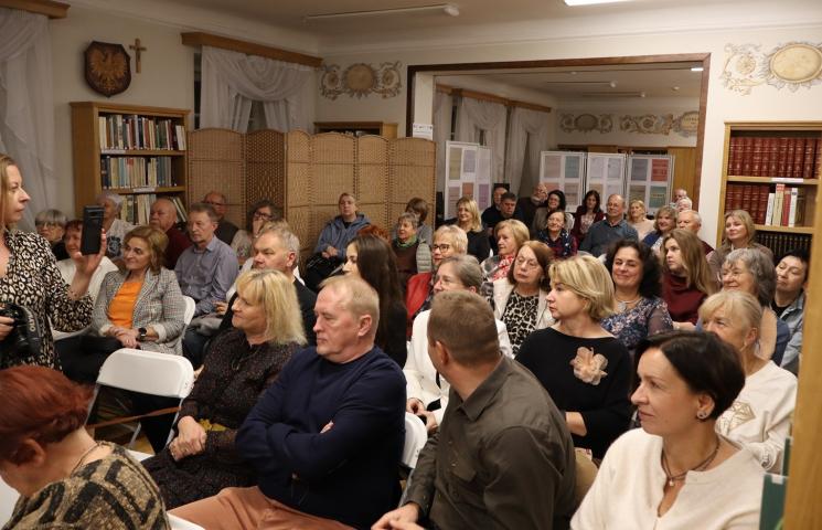 kolorowe zdjęcie, grupa ludzi siedzi na krzesłach, zdjęcie na tle książek