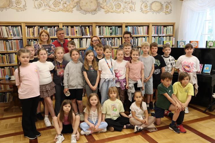 kolorowe zdjęcie, 3 osoby, 2 kobiety i 1 mężczyzna, pozują do zdjęcia na tle książek 
