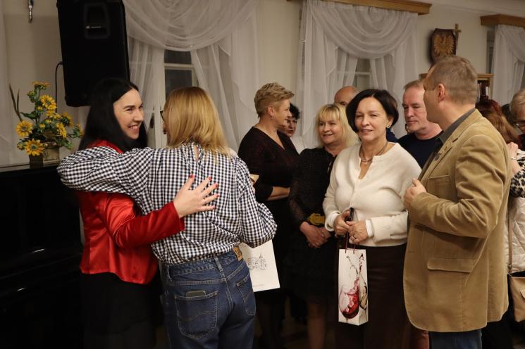 kolorowe zdjęcie, grupa ludzi siedzi na krzesłach, zdjęcie na tle książek