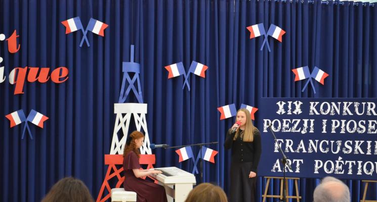 3 osoby siedza jesdna stoi i spiewa