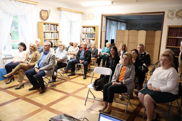 7 osób, 5 siedzi, 2 osoby przemawiają