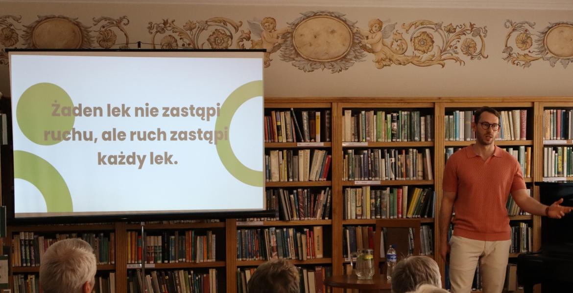 kolorowe zdjęcie, 6 osób, 5 siedzi, 1 stoi i przeprowadza prezentację