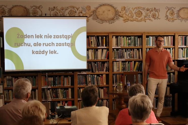 kolorowe zdjęcie, 6 osób, 5 siedzi, 1 stoi i przeprowadza prezentację